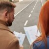Two business professionals reviewing documents together on an outdoor street.
