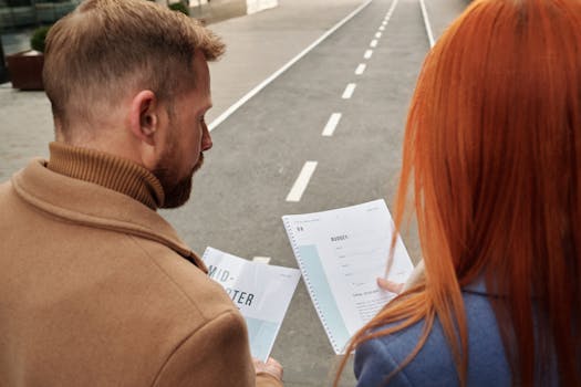 Two business professionals reviewing documents together on an outdoor street.