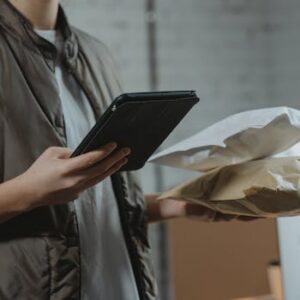 A person using a tablet to manage packages in an indoor setting, highlighting technology and logistics.