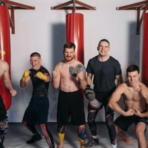 Six muscular men posing confidently in a gym, showcasing fighting spirit and camaraderie.