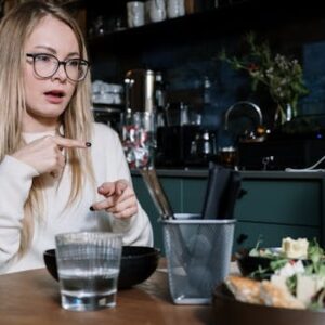 Woman using sign language while dining at a café, with focus on gesture communication.