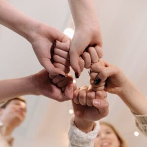 Close-up of a diverse group joining fists in a show of unity and teamwork indoors.