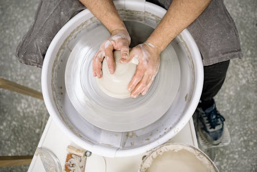 Hands shaping clay on a pottery wheel, emphasizing craftsmanship and artistry.