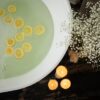 Overhead shot of a bath with lemon slices, candles, and flowers for a soothing spa ambiance.