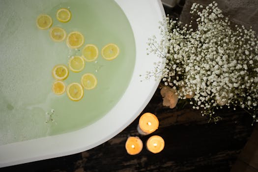 Overhead shot of a bath with lemon slices, candles, and flowers for a soothing spa ambiance.