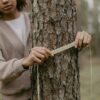 Young woman measuring tree trunk in a forest setting for environmental research.