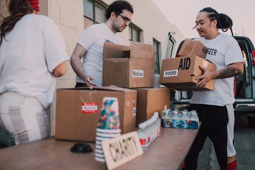Volunteers loading aid boxes with food and medicine from a van outdoors.