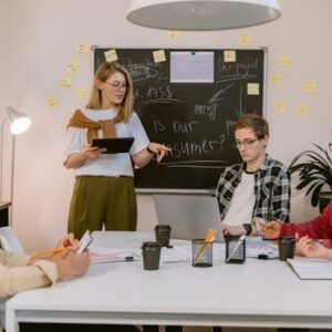 A diverse group of young professionals collaborating in a modern office setting with laptops and notes.
