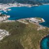 Stunning aerial view of a city by the coastline with azure waters and lush greenery.