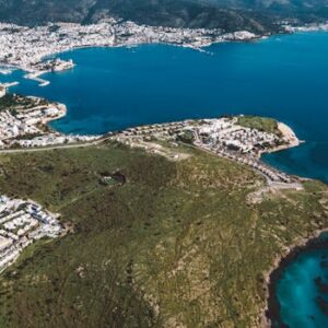Stunning aerial view of a city by the coastline with azure waters and lush greenery.