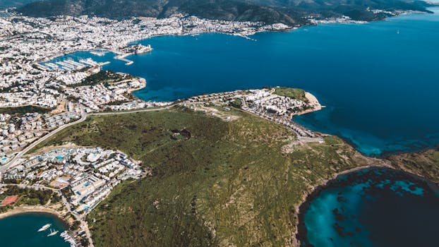 Stunning aerial view of a city by the coastline with azure waters and lush greenery.