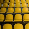 Vertical shot of empty yellow stadium seats arranged in rows outdoors.