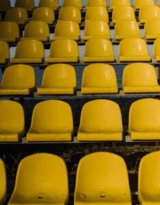 Vertical shot of empty yellow stadium seats arranged in rows outdoors.