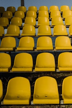 Vertical shot of empty yellow stadium seats arranged in rows outdoors.