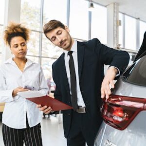 Businessman and customer discussing car purchase inside modern showroom.