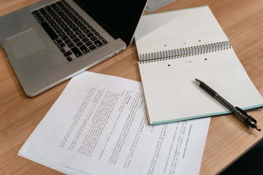 A professional workspace featuring a laptop, documents, and a notepad for productive work.