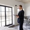 Real estate agent in a black blazer using a tablet inside a furnished home.