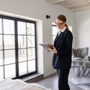 Real estate agent in a black blazer using a tablet inside a furnished home.