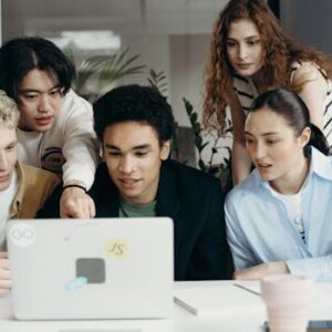 Diverse group of young professionals collaborating on a laptop project in a modern office setting.