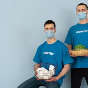 Two volunteers wearing masks holding supplies and plants, promoting charity and environmental protection.