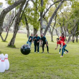 Group enjoying an outdoor team building event with bowling in a park setting.