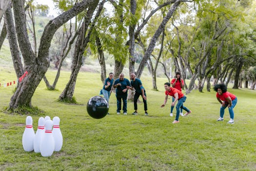 Group enjoying an outdoor team building event with bowling in a park setting.