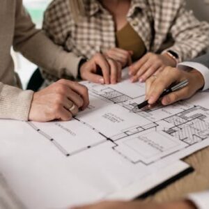 Group examining house floor plans with a real estate agent, highlighting home buying process.