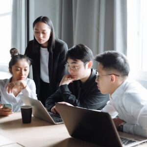 A group of Asian professionals engaged in a collaborative business meeting in a bright office setting.