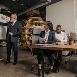 Business professionals engage in a team meeting with a whiteboard presentation in a modern office.