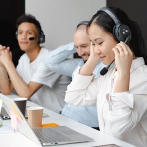 Diverse team of call center agents using laptops and headsets in a modern office setting.