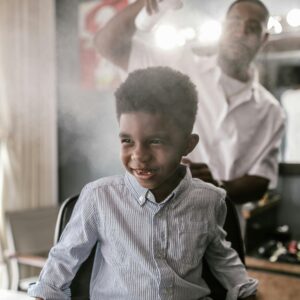 Smiling child enjoying a haircut in a lively barbershop atmosphere. Playful and cheerful scene.