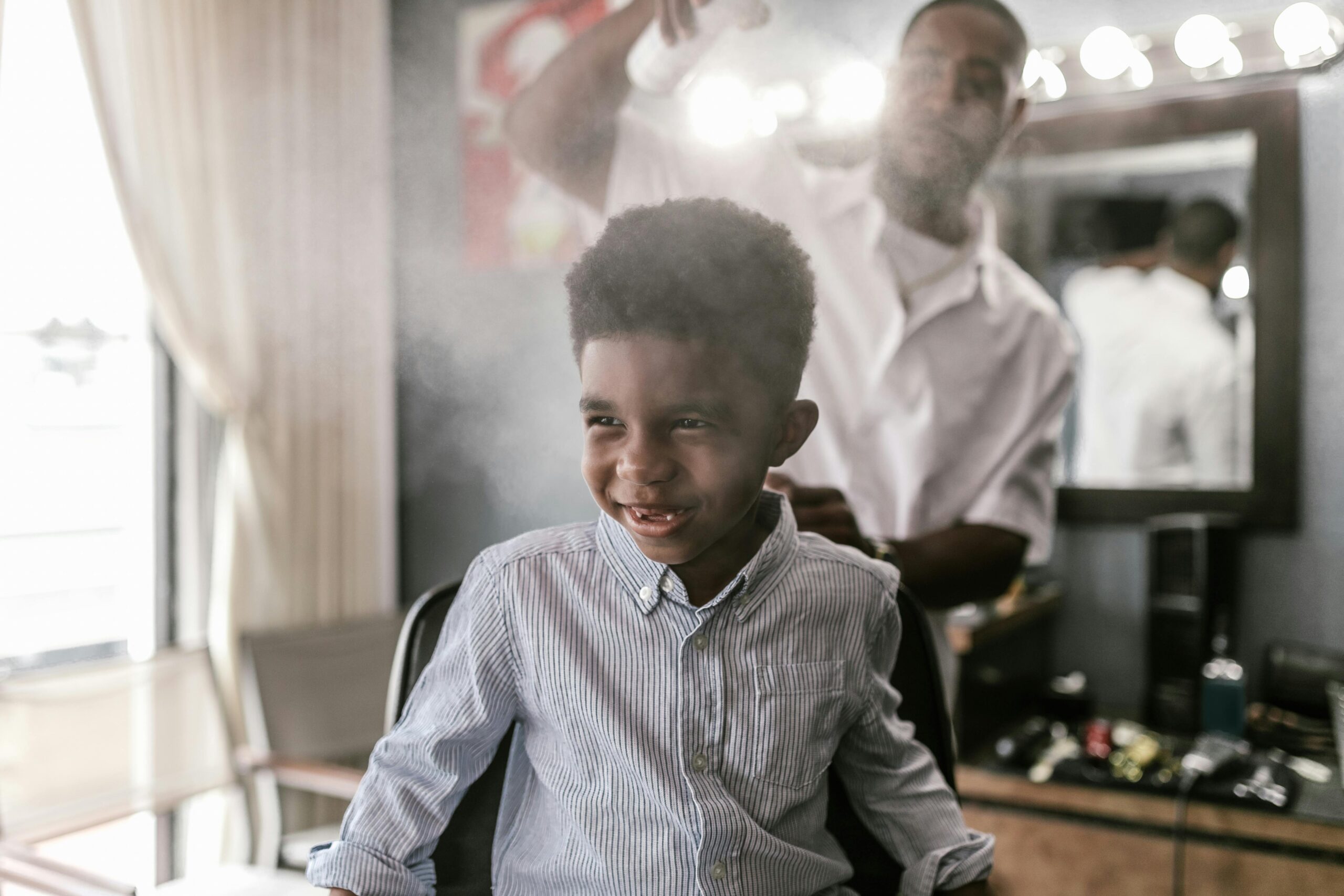 Smiling child enjoying a haircut in a lively barbershop atmosphere. Playful and cheerful scene.