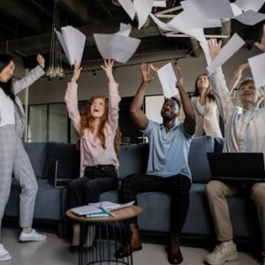 A diverse group of coworkers celebrating success by throwing papers in an office.
