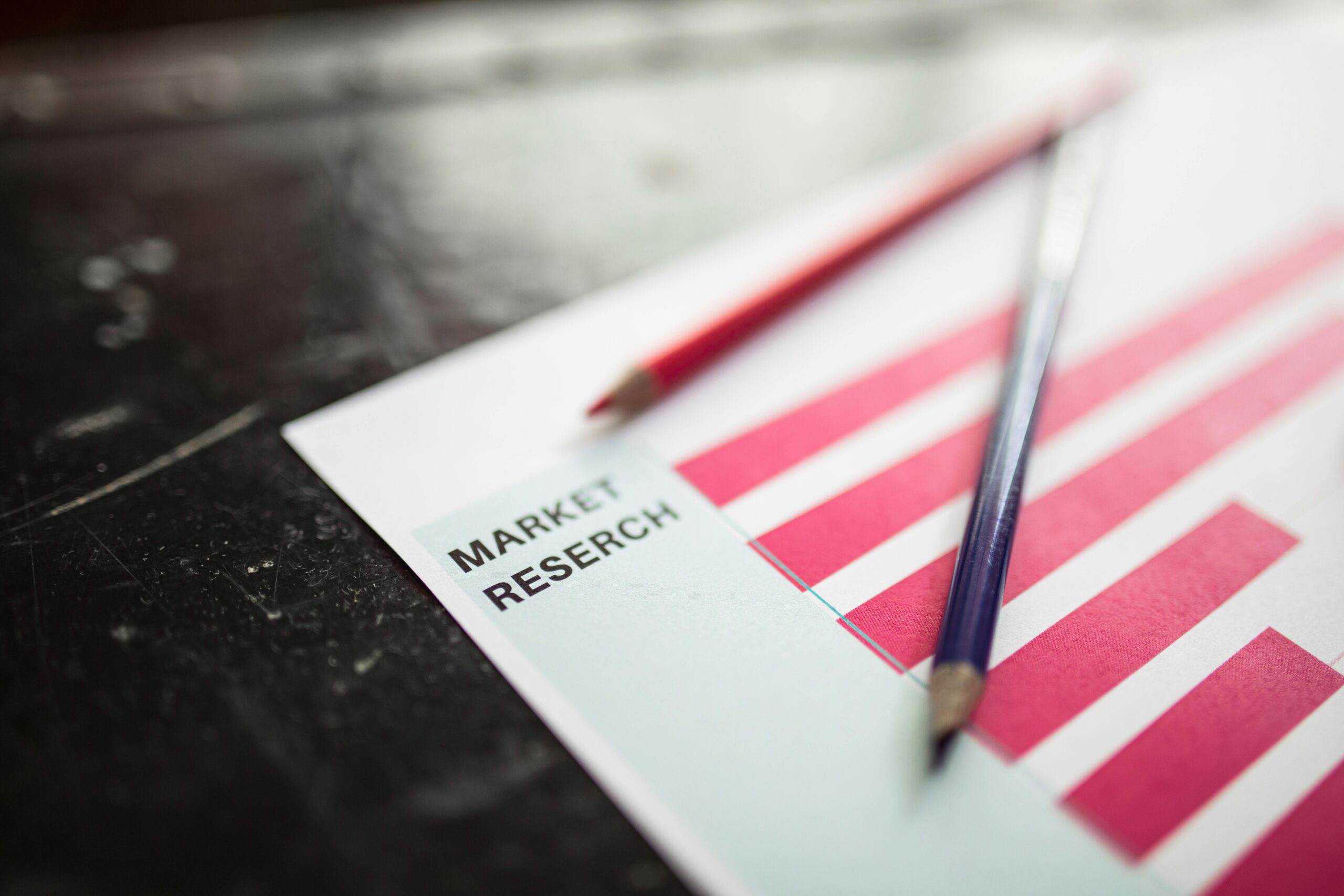 Close-up of market research paper with red graph bars and pencils, emphasizing business analysis.