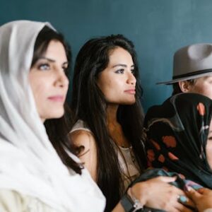 Diverse group of women wearing headscarves and hats, captured in an indoor setting.