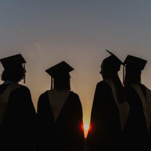 A group of graduates in caps and gowns silhouetted against a beautiful sunset, symbolizing achievement.