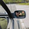 A person with a gun captured in the car's side mirror, suggesting a mysterious scenario.