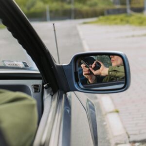 A person with a gun captured in the car's side mirror, suggesting a mysterious scenario.