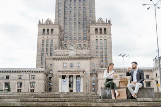 Couple enjoying lunch outdoors on steps of iconic Warsaw landmark.