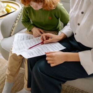 A child and teacher study music sheet indoors with a flute visible. Music learning at home.