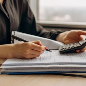 Close-up of person using a calculator with financial documents in an office.