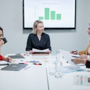 Businesswomen engaged in a productive meeting in a modern conference room with charts displayed.