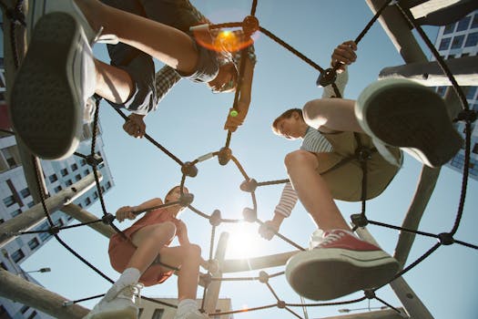Dynamic view of kids playing and climbing on a rope structure in an urban playground under sunlight.