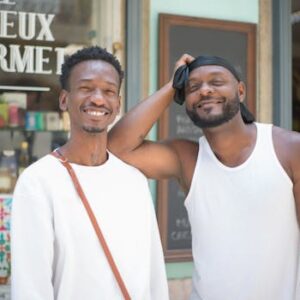 Two friends enjoying a sunny day outside a café in Portugal, showcasing camaraderie and happiness.