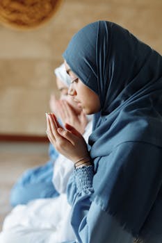 Two Muslim women in hijabs praying inside a mosque, exemplifying faith and spirituality.