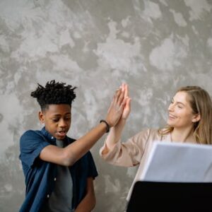 A child and teacher celebrate success with a high five during piano lessons, ensuring a positive learning environment.