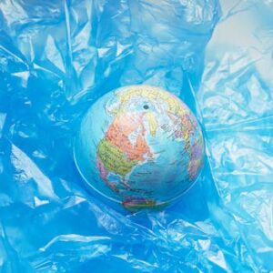 A globe wrapped in blue plastic, symbolizing global pollution and environmental issues.