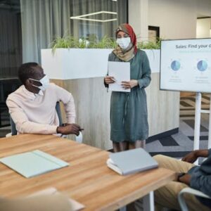 Team meeting with masks and a presentation on customer sales analysis.