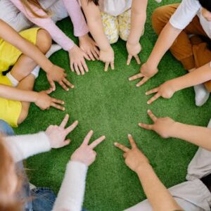 Children sitting in a circle playing fun team games on artificial grass.