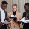 A multi-ethnic group of professionals reviewing documents together in a corporate setting.